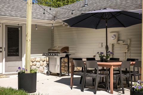 Private patio with grill, shaded dining table, and cozy string lights