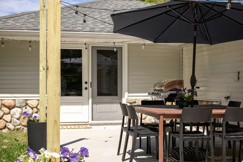 Private patio with dining set, grill, umbrella, and cozy string lights