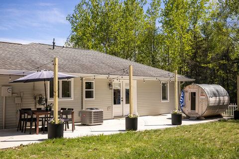 Private backyard patio with dining area, string lights, and barrel sauna