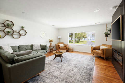 Bright, spacious living room with large windows, fireplace, and cozy seating