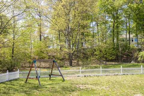 Private fenced backyard with swing set and peaceful wooded views
