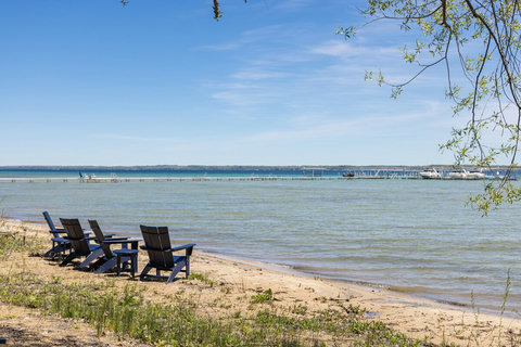 Private sandy beach with Adirondack chairs and serene lake views