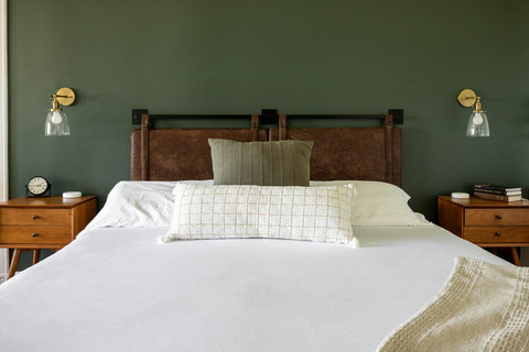 Stylish bedroom with leather headboard and calming green accent wall