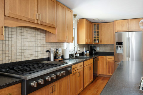 Spacious gourmet kitchen with gas range, stone counters, and warm wood cabinetry