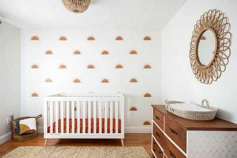 Bright boho nursery with sun accent wall, crib, and stylish natural touches