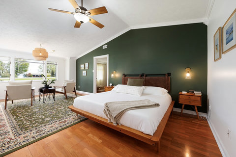 Spacious king bedroom with sitting area, vaulted ceiling, and bright windows