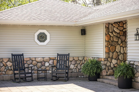 Cozy stone-accented patio with rocking chairs for peaceful outdoor lounging