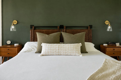 Elegant bedroom with green accent wall, leather headboard, and cozy styling