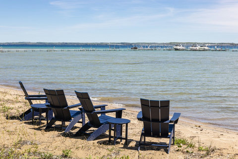 Relax in Adirondack chairs on a peaceful sandy waterfront beach