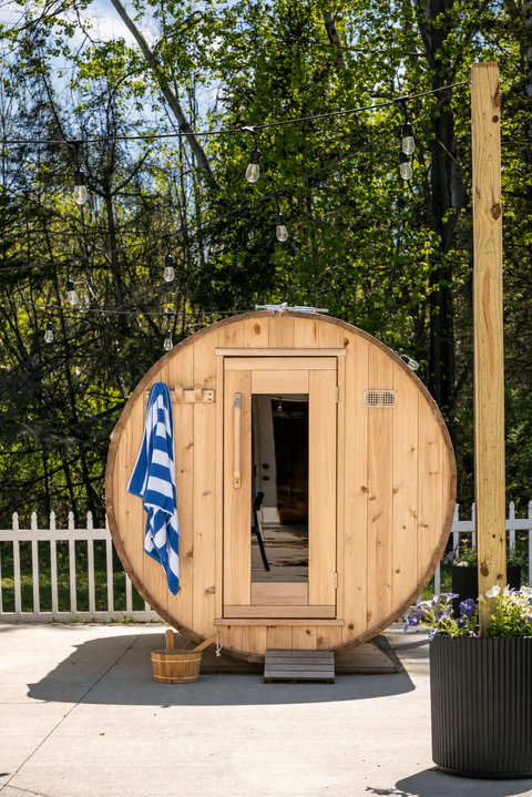 Private barrel sauna with patio seating and serene wooded ambiance