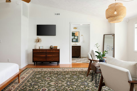 Bright, spacious bedroom with stylish seating, TV, and vintage charm