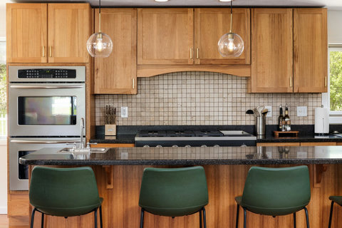 Warm modern kitchen with granite island, gas cooktop, and bar seating