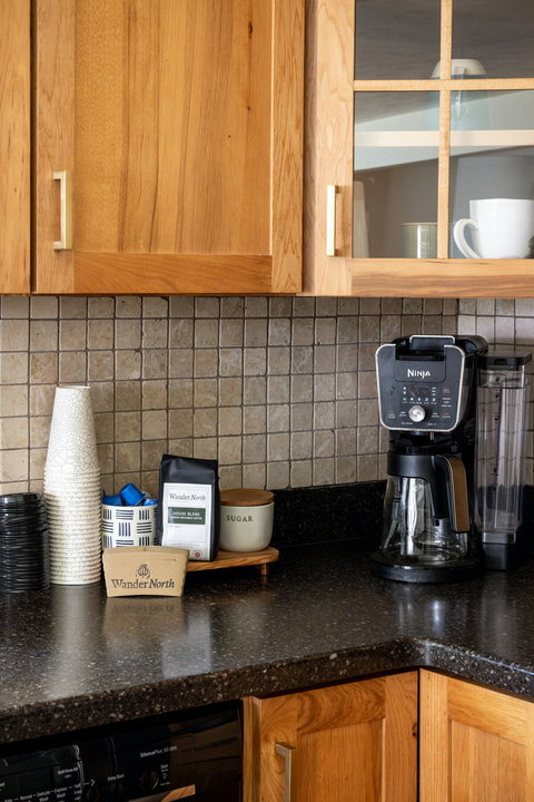 Inviting kitchen coffee station with stocked essentials and warm wood finishes