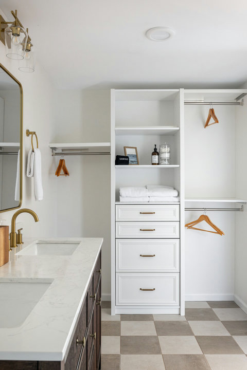 Bright custom closet and double vanity with elegant brass finishes