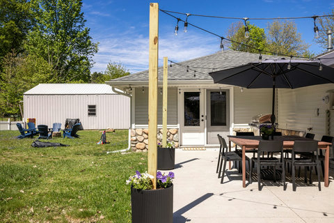Spacious backyard patio with dining, grill, string lights, and fire pit seating