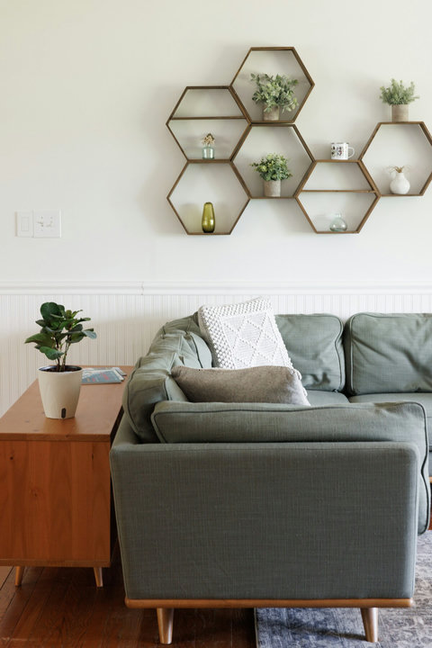 Stylish living room with cozy green sofa and modern geometric wall decor