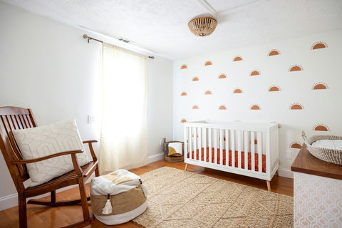 Bright boho nursery with crib, rocking chair, and sunny accent wall