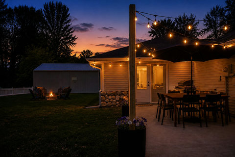 Twilight patio with string lights, outdoor dining, and a cozy fire pit