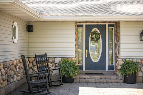 Charming covered entry with rocking chairs and elegant stone accents