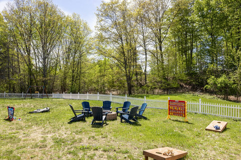 Private fenced backyard with fire pit, Adirondack seating, and lawn games