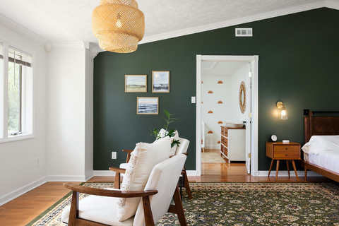 Moody green bedroom with cozy seating and charming ensuite bath view