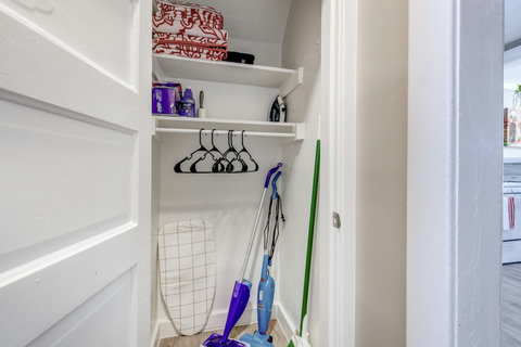 Hallway closet with extra towels, cleaning supplies, an iron and ironing board, and instructions on how to use equipment in the home.