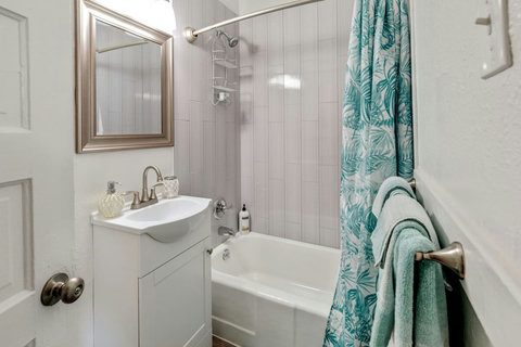 Bathroom with a sink, bathtub, shower, toilet, towels, shampoo and soap.