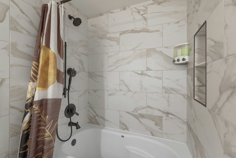 Shower and bathtub fully stocked with shampoo, conditioner, body wash