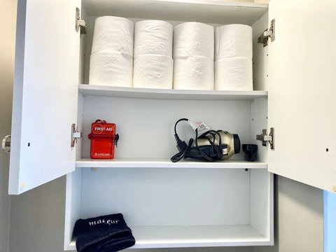 Toilet paper always fully-stocked, a hairdryer, first aid kit, and makeup washcloth