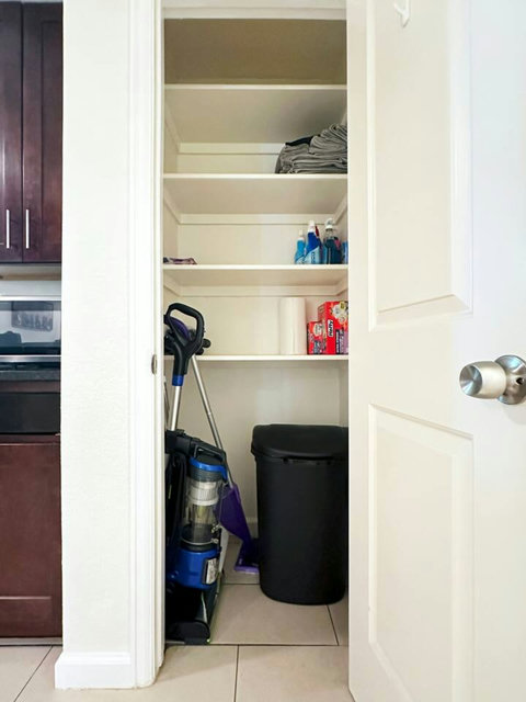 Closet in kitchen area with cleaning supplies, extra towels, and storage