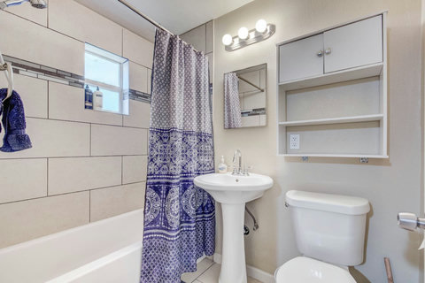 Fully-stocked bathroom with a sink, toilet, bathtub/shower, and storage space