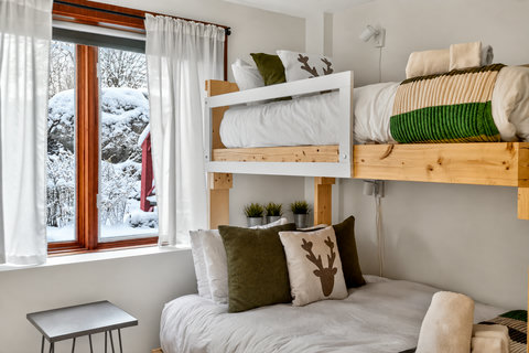 Cozy bunk room with snowy views and warm, modern alpine touches