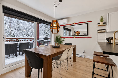 Bright dining space with snowy deck views, grill, and cozy mountain style