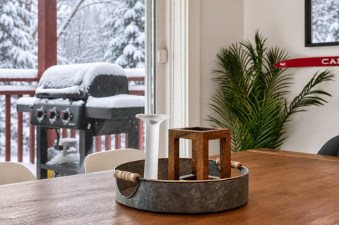 Cozy dining space with snowy deck views and a private outdoor grill