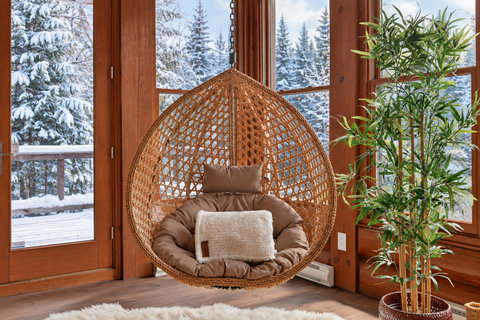 Cozy hanging chair with snowy forest views and warm cabin charm