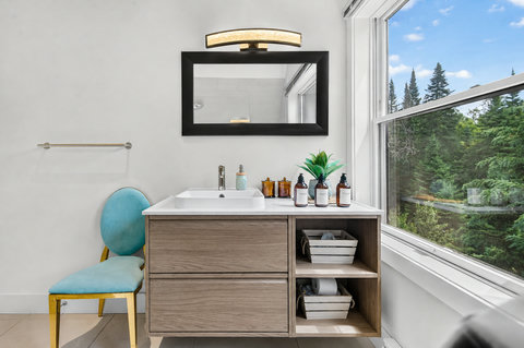 Bright modern bath with forest views and stylish vanity