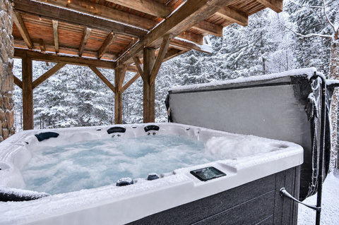 Soak in the snowy forest from this private covered outdoor hot tub