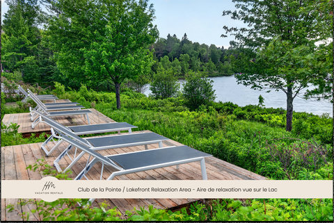 Serene lakefront lounge deck with recliners and lush nature views