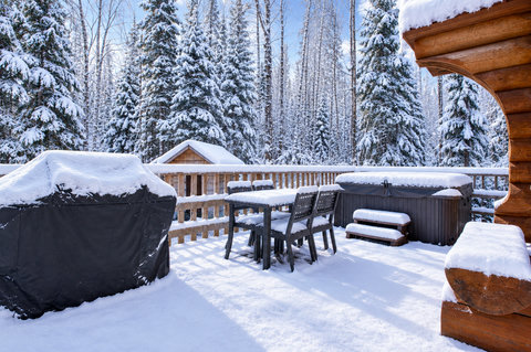 Snowy private deck with hot tub, grill, and serene forest views