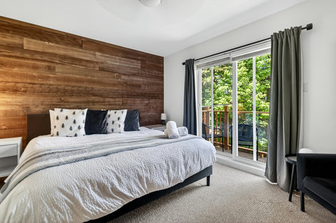 Bright bedroom with wood accent wall and private balcony views