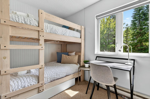 Bright bunk room with workspace and serene tree-lined views