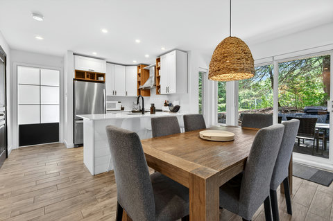 Bright modern kitchen-dining space with patio access and leafy views