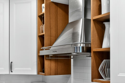 Designer kitchen with sleek stainless hood and warm wood shelving