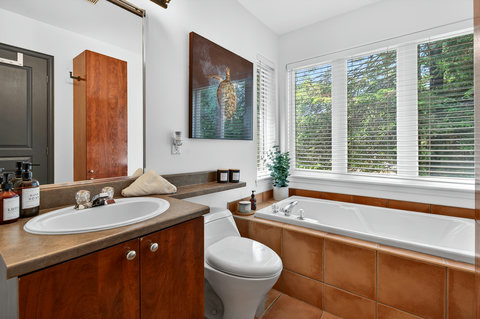 Bright spa-like bathroom with soaking tub and peaceful treetop views