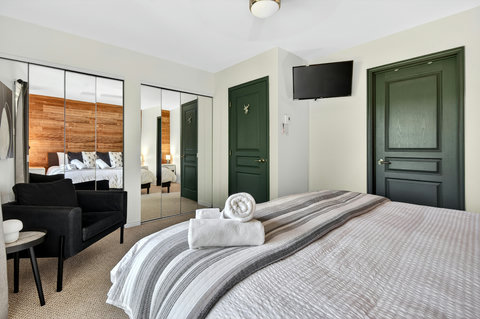 Bright, cozy bedroom with mirrored closets, TV, and stylish design