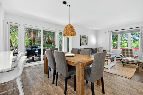 Bright open living space with patio access, outdoor dining, and forest views