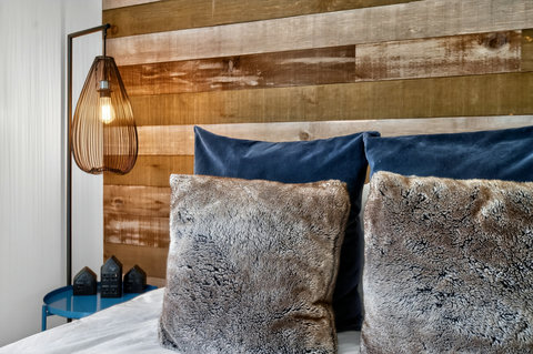 Cozy modern bedroom with wood accent wall and warm designer lighting
