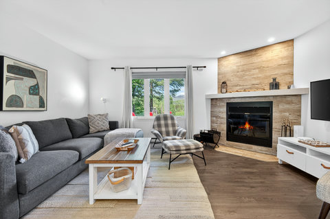 Cozy living room with fireplace, sectional seating, and bright window views