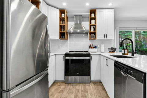 Bright modern kitchen with stainless appliances and forest-view window