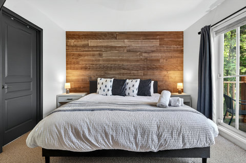Cozy king bedroom with wood accent wall and private deck views